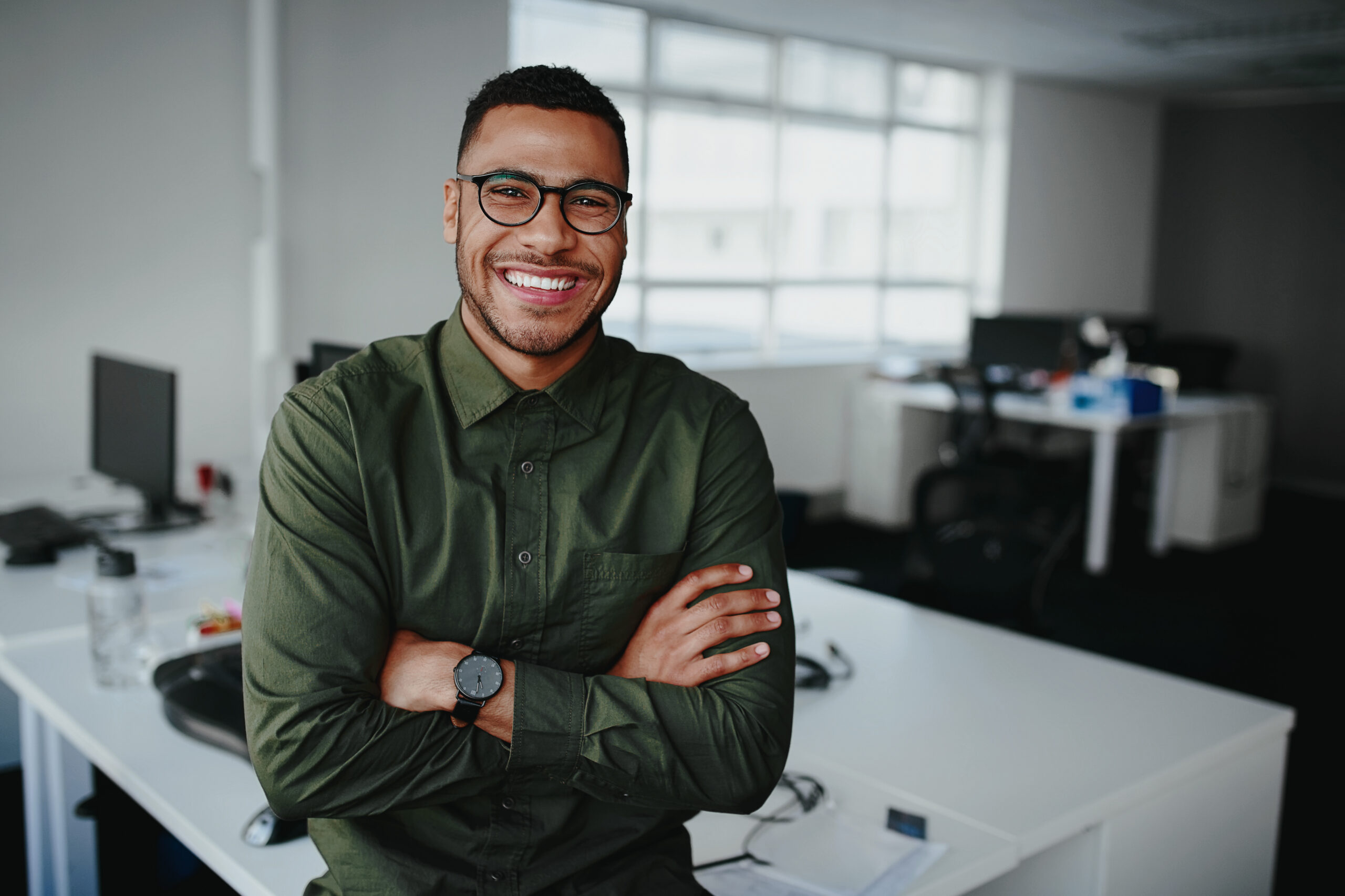 Portrait of a happy confident young african american businessman standing with his arms crossed looking at camera