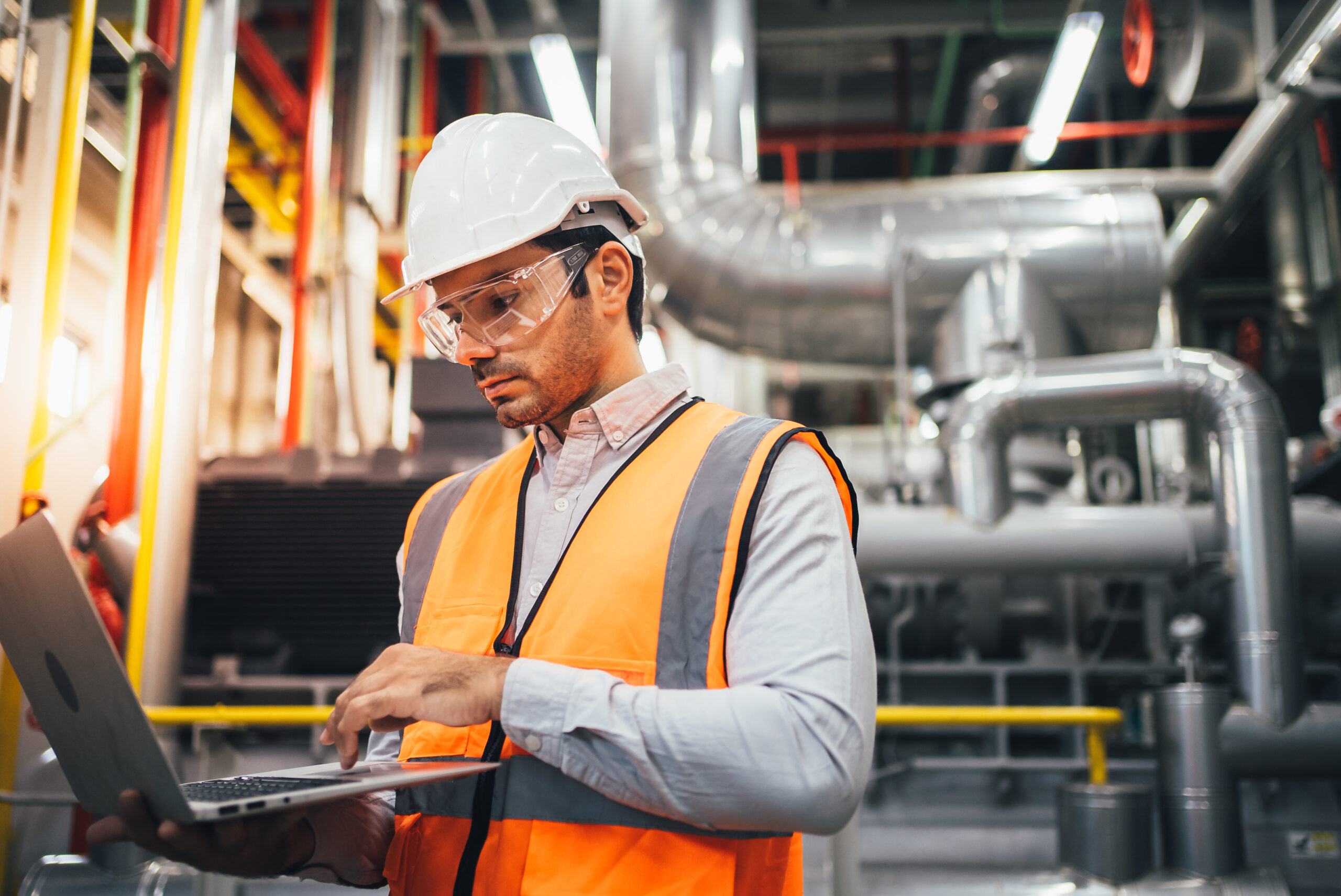 Professional worker of modern factory using laptop controlling p